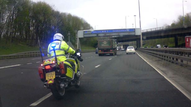 Car narrowly misses police bike as it swerves into fast lane on British motorway